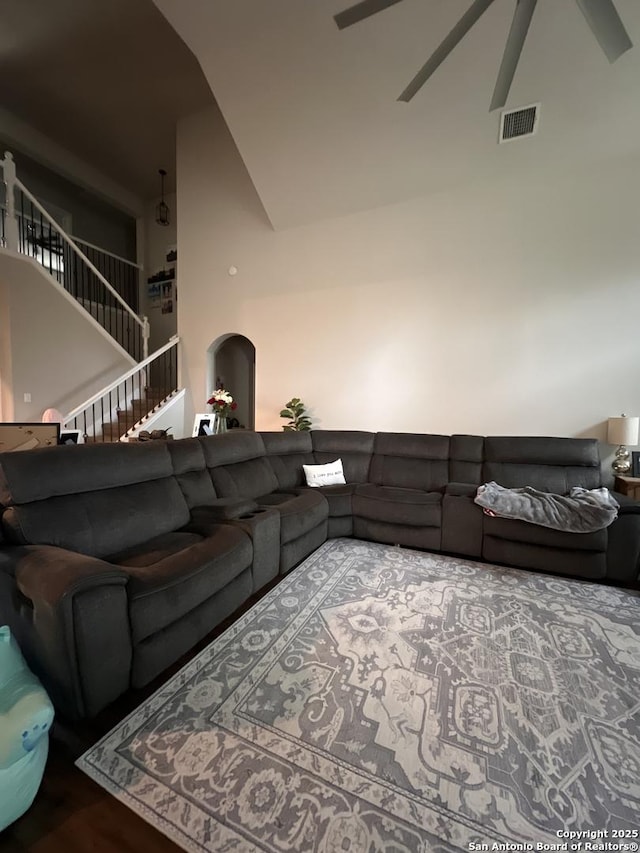 living room featuring high vaulted ceiling, stairs, visible vents, and a ceiling fan