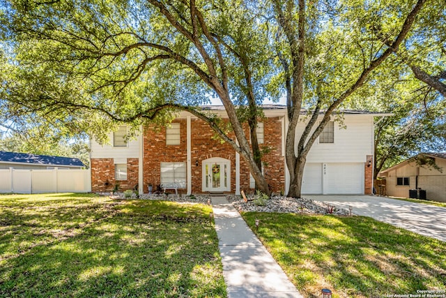 split foyer home featuring an attached garage, brick siding, fence, driveway, and a front yard