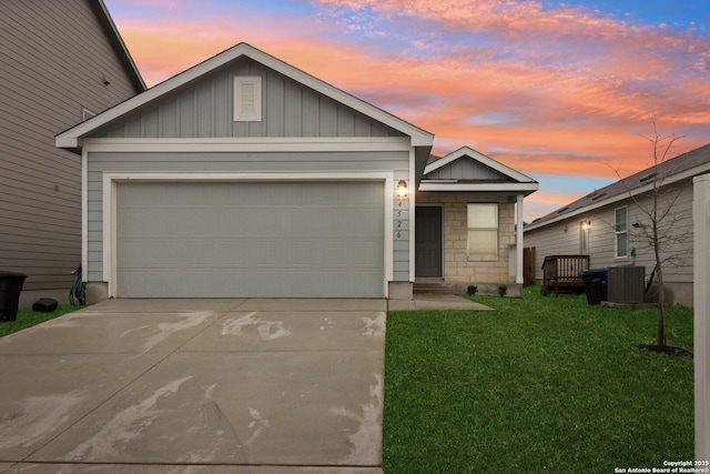 view of front of property with an attached garage, board and batten siding, central AC, driveway, and a front lawn