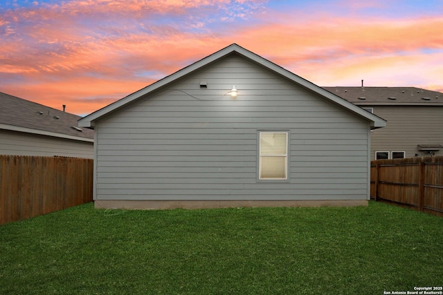 view of side of home featuring a fenced backyard and a lawn