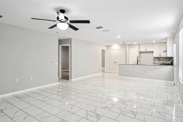 unfurnished living room with baseboards, visible vents, a ceiling fan, marble finish floor, and a sink