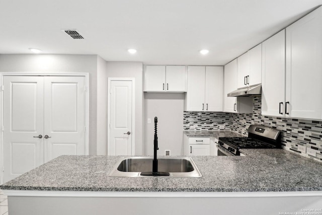 kitchen featuring white cabinets, stainless steel range with gas stovetop, a sink, and a peninsula