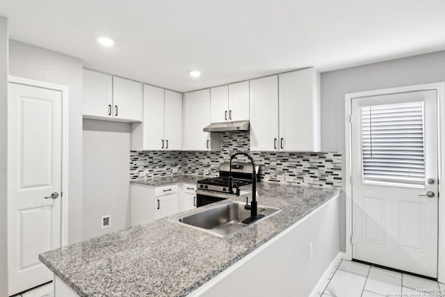 kitchen with stainless steel gas stove, a peninsula, white cabinetry, and under cabinet range hood