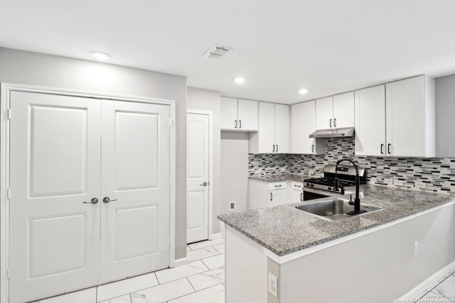 kitchen featuring marble finish floor, stainless steel gas stove, white cabinets, a peninsula, and under cabinet range hood