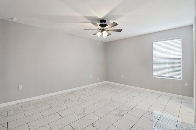 unfurnished room with marble finish floor, a ceiling fan, and baseboards