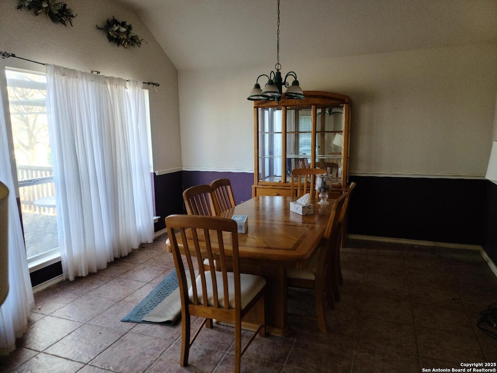 dining space with lofted ceiling, an inviting chandelier, and tile patterned floors