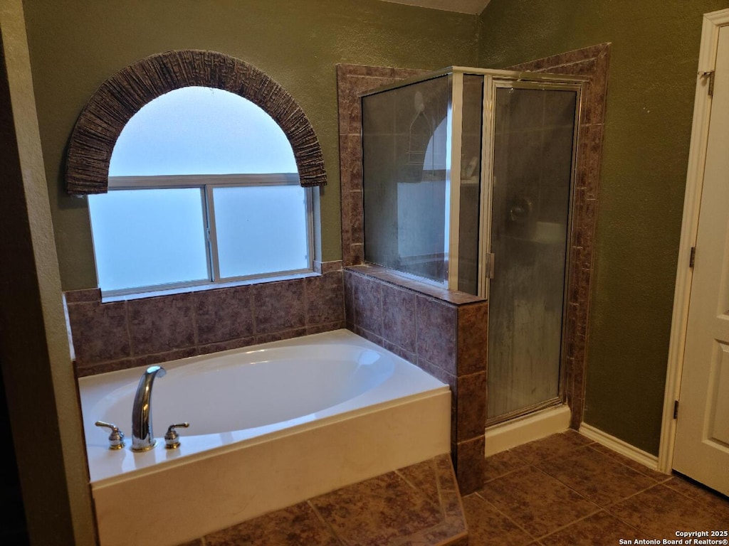 bathroom with a garden tub, a textured wall, a shower stall, and tile patterned floors