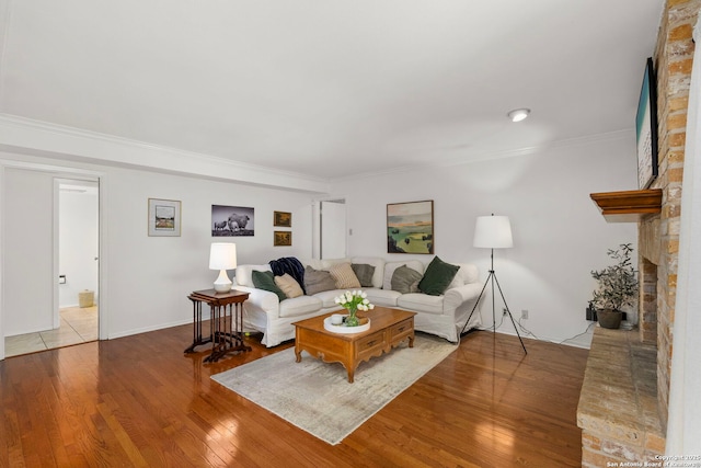 living area featuring a brick fireplace, wood-type flooring, and ornamental molding