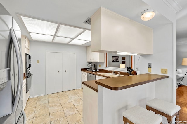 kitchen with a peninsula, appliances with stainless steel finishes, a breakfast bar area, and a sink