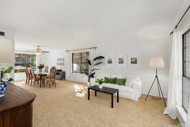 living room with light carpet, a healthy amount of sunlight, visible vents, and a ceiling fan