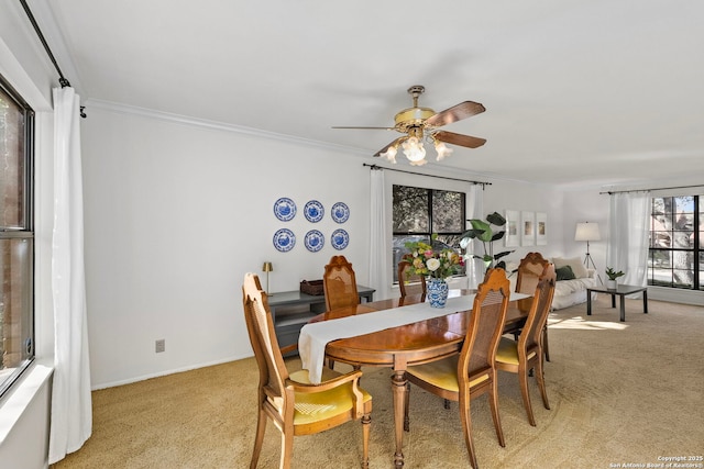 dining space featuring ornamental molding, light carpet, and a ceiling fan