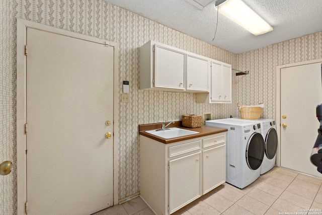 laundry area featuring light tile patterned flooring, a sink, cabinet space, washer and clothes dryer, and wallpapered walls