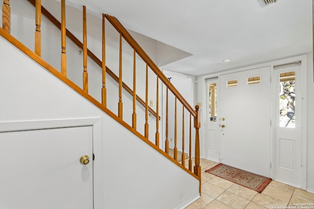 entryway with light tile patterned floors and stairway