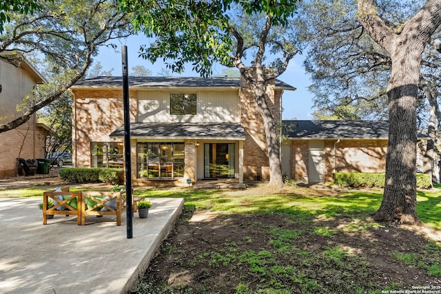 back of property with brick siding and a patio