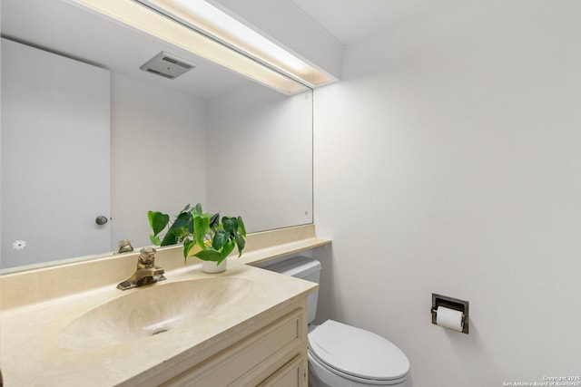 half bathroom with toilet, vanity, and visible vents