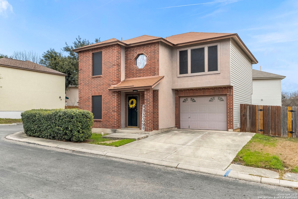 view of front of house featuring driveway, brick siding, an attached garage, and fence