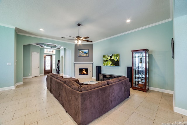 living room featuring light tile patterned floors, a fireplace, arched walkways, and crown molding