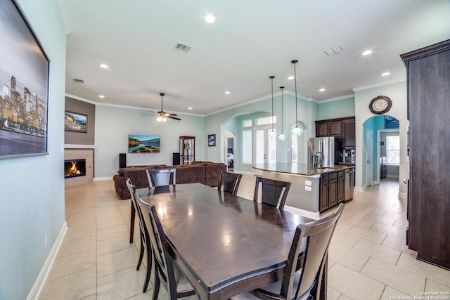 dining space with a fireplace, arched walkways, and ornamental molding