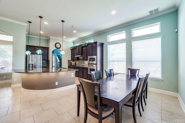 dining room with light tile patterned flooring, baseboards, visible vents, and ornamental molding