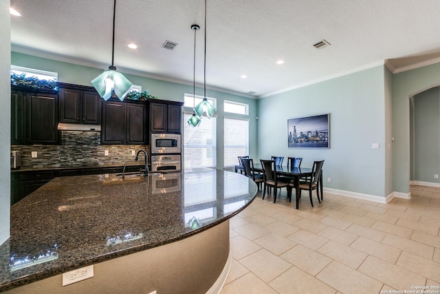 kitchen featuring dark stone counters, hanging light fixtures, appliances with stainless steel finishes, and visible vents