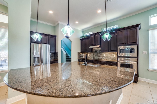 kitchen featuring dark brown cabinetry, appliances with stainless steel finishes, pendant lighting, and dark stone counters