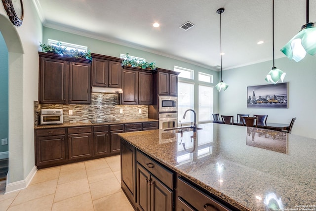 kitchen featuring stainless steel appliances, visible vents, dark brown cabinets, light stone countertops, and pendant lighting