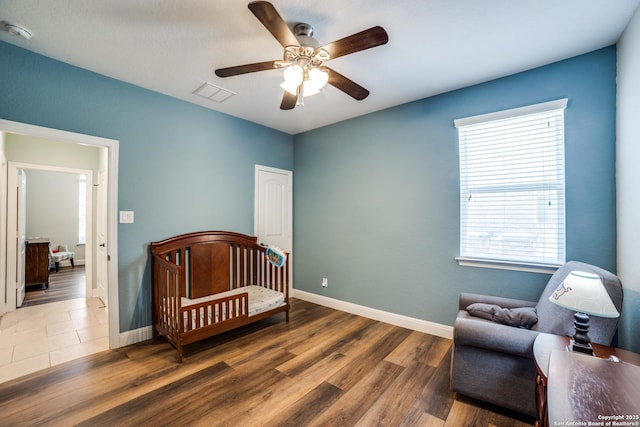 bedroom with dark wood-style floors, visible vents, ceiling fan, and baseboards