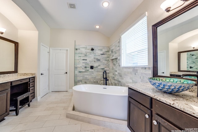 full bath with lofted ceiling, a soaking tub, visible vents, and vanity