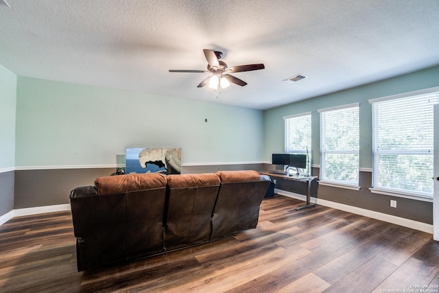 living room with a ceiling fan, baseboards, visible vents, and dark wood-type flooring