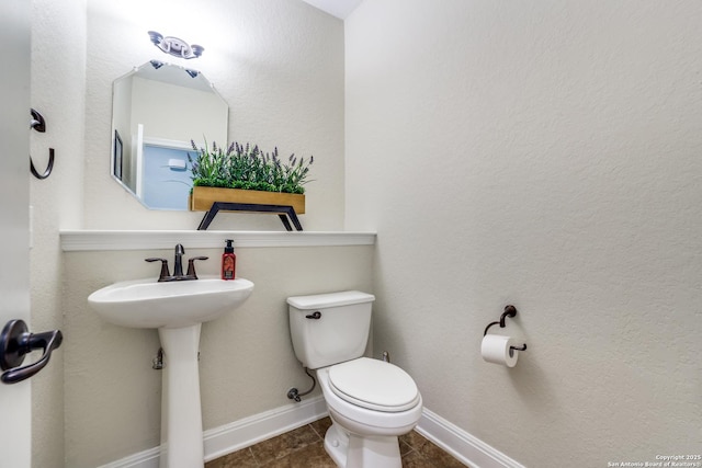 half bath with toilet, tile patterned flooring, and baseboards