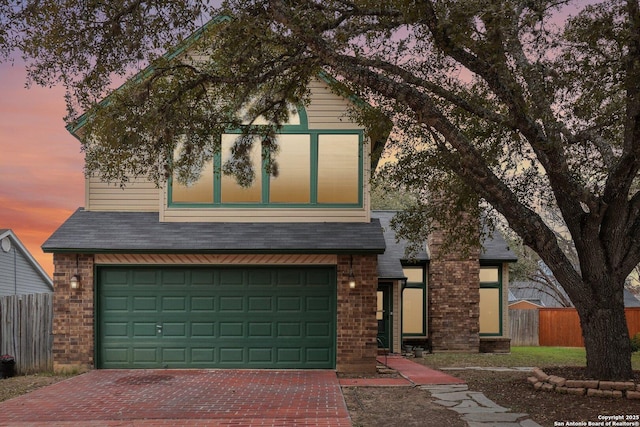 view of front of house featuring roof with shingles, fence, decorative driveway, and brick siding