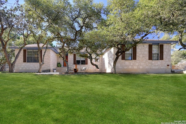 back of property featuring stone siding and a lawn