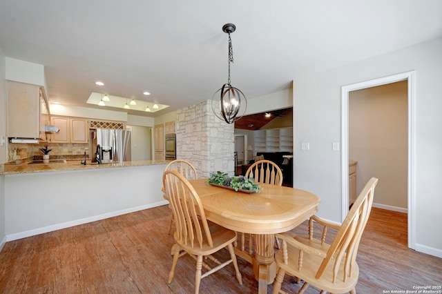 dining room featuring recessed lighting, light wood-type flooring, an inviting chandelier, and baseboards