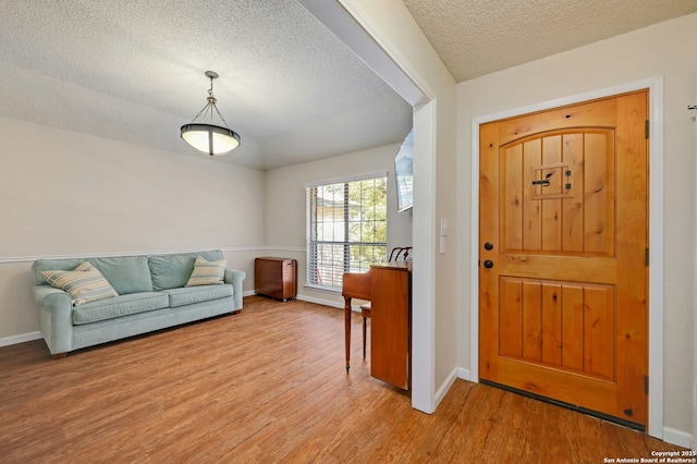 entryway with light wood-style floors, a textured ceiling, and baseboards