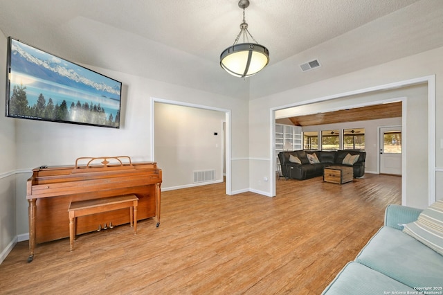 living room with baseboards, visible vents, and light wood finished floors