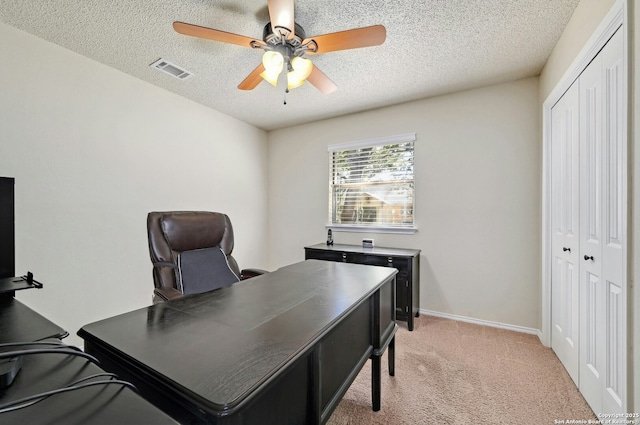 office area featuring ceiling fan, a textured ceiling, light colored carpet, visible vents, and baseboards