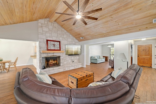 living room with wooden ceiling, beamed ceiling, wood finished floors, and a stone fireplace