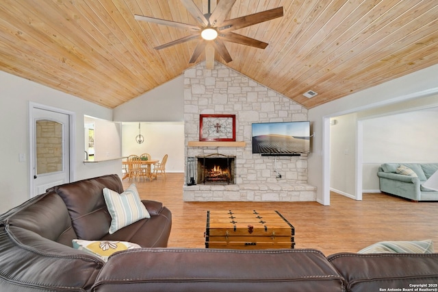 living room featuring wood ceiling, vaulted ceiling, wood finished floors, and a stone fireplace