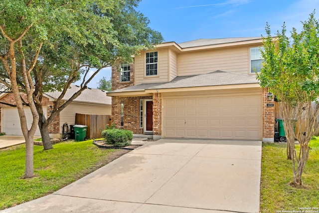 traditional-style house with driveway, brick siding, a front yard, and fence