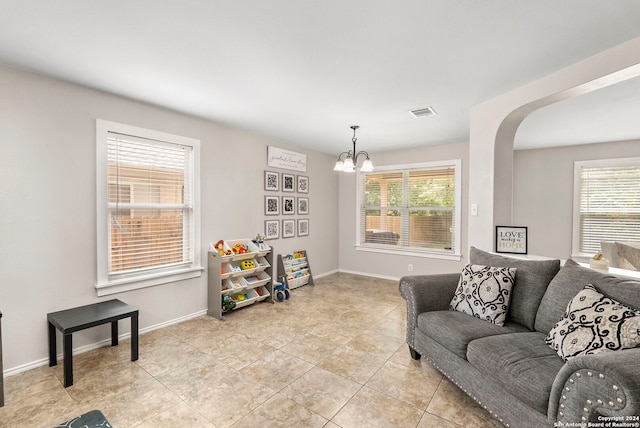 living area with a wealth of natural light, arched walkways, baseboards, and an inviting chandelier