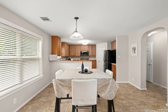 dining room featuring arched walkways, light tile patterned flooring, visible vents, and baseboards