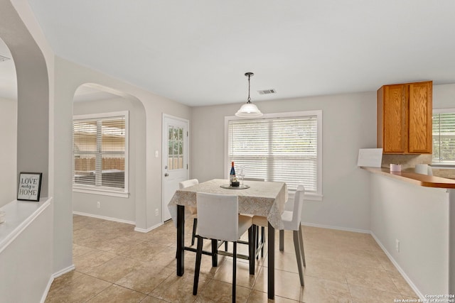 dining room featuring a wealth of natural light, visible vents, arched walkways, and baseboards