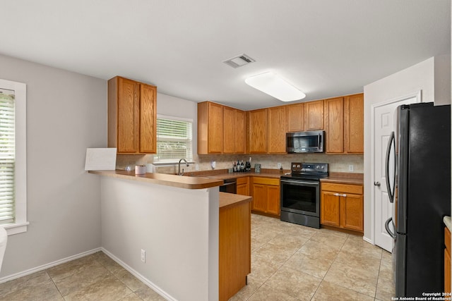 kitchen featuring visible vents, backsplash, appliances with stainless steel finishes, brown cabinetry, and a peninsula