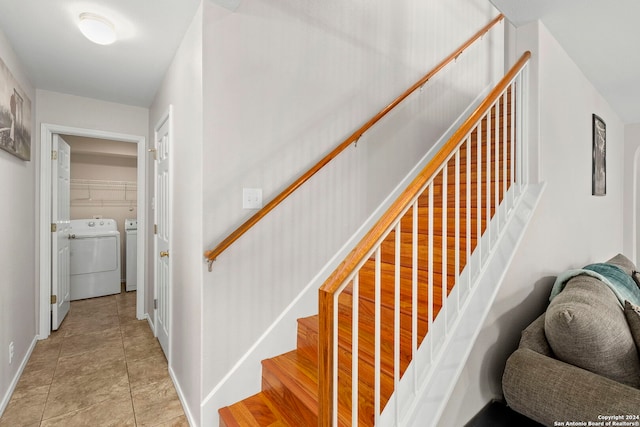 stairway featuring tile patterned flooring, washing machine and clothes dryer, and baseboards