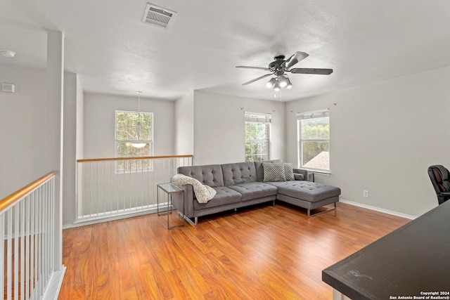 living room featuring a textured ceiling, wood finished floors, visible vents, and baseboards