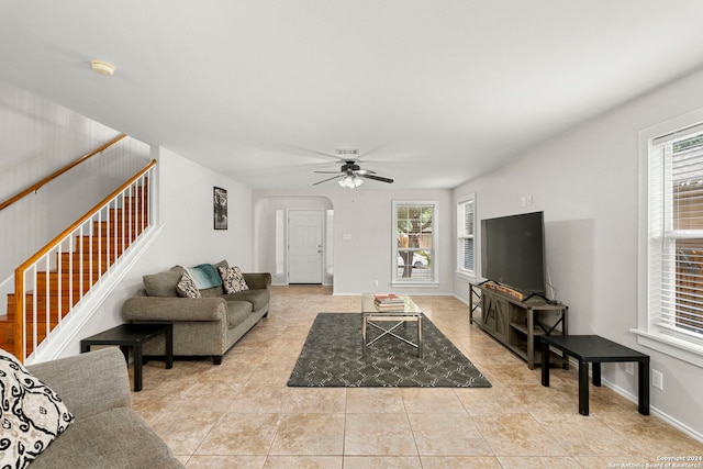 living area with a healthy amount of sunlight, stairway, arched walkways, and light tile patterned flooring