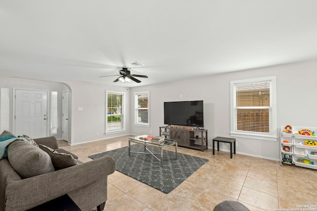 living area with arched walkways, visible vents, baseboards, and light tile patterned floors