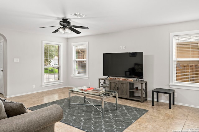 living area with a ceiling fan, arched walkways, visible vents, and baseboards