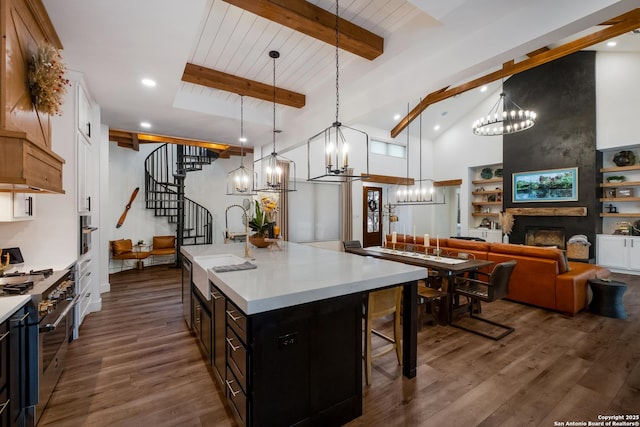 kitchen featuring stainless steel appliances, open floor plan, light countertops, an island with sink, and pendant lighting