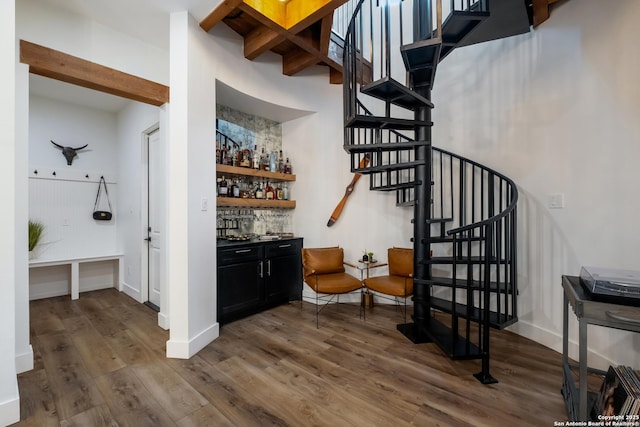 interior space with a dry bar, stairway, dark wood-type flooring, beamed ceiling, and baseboards